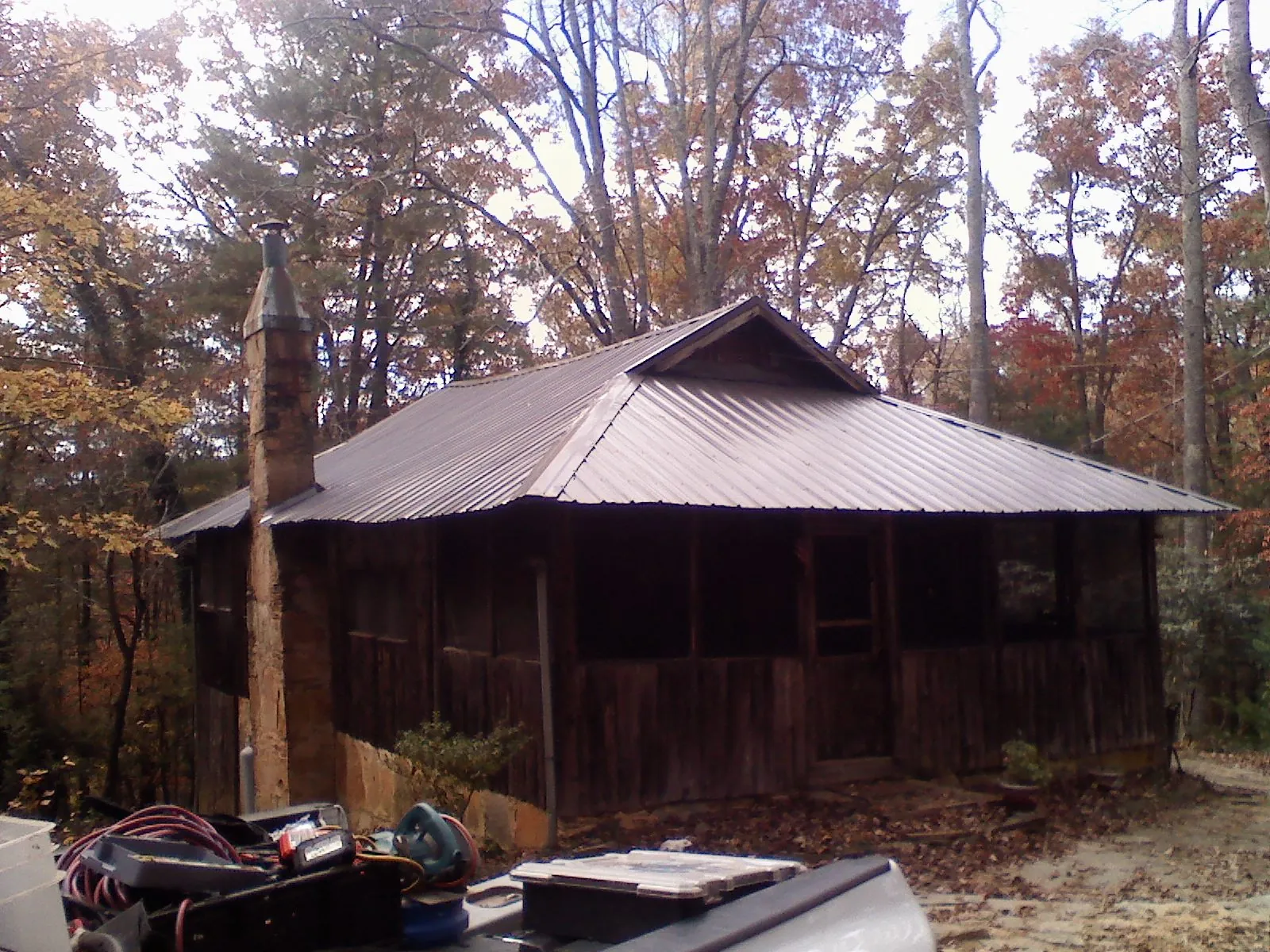 Brown metal hip roof on an old cabin with a stone chimney in Deerfield