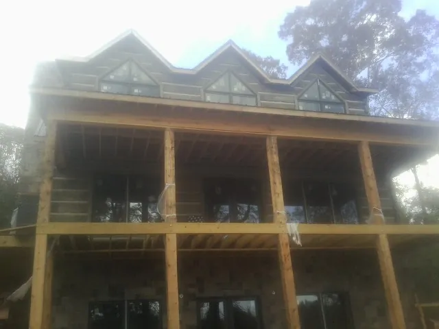 Dormers and porch framing on a large log home under construction — Roof Coating work by our crew in Deerfield
